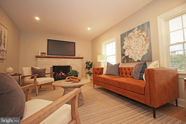 living room featuring wood-type flooring and a brick fireplace