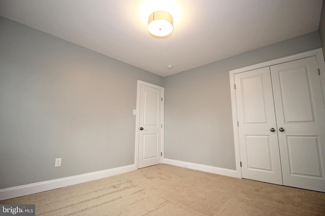 unfurnished bedroom featuring light colored carpet and a closet