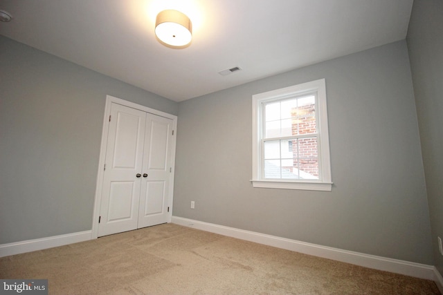 unfurnished bedroom featuring a closet and light colored carpet