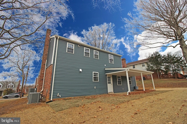 rear view of property with covered porch, central AC, and a lawn