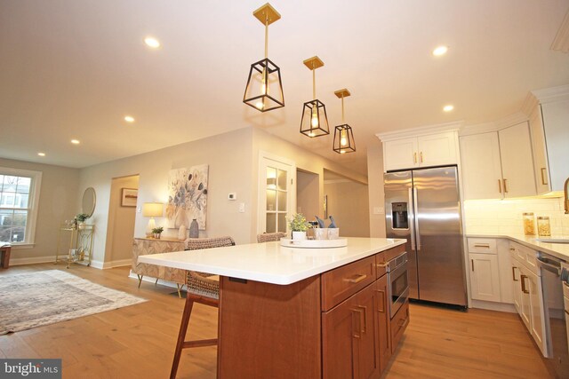 kitchen featuring stainless steel appliances, white cabinetry, pendant lighting, a kitchen island, and a breakfast bar