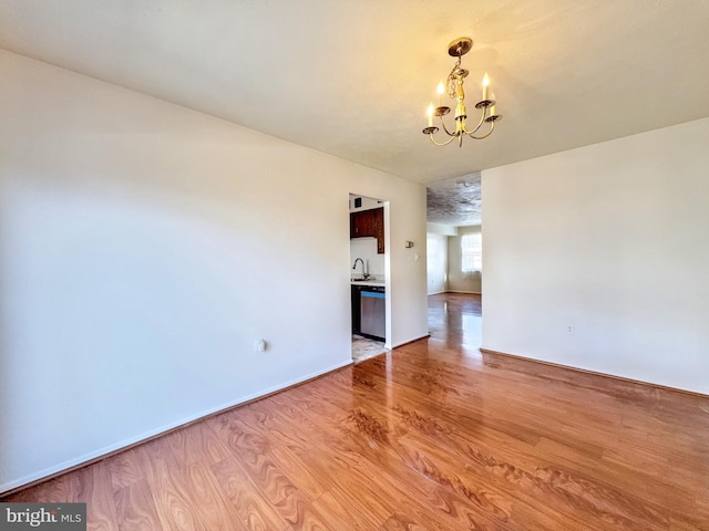 unfurnished room with sink, light hardwood / wood-style flooring, and a chandelier