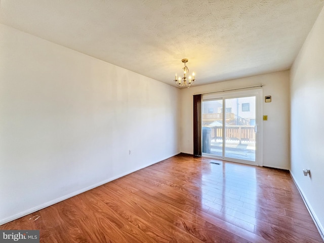 unfurnished room with a chandelier, a textured ceiling, and light wood-type flooring