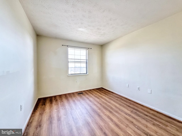 unfurnished room featuring hardwood / wood-style floors and a textured ceiling