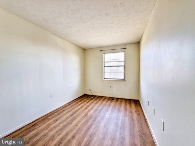 unfurnished room with a textured ceiling and light hardwood / wood-style floors