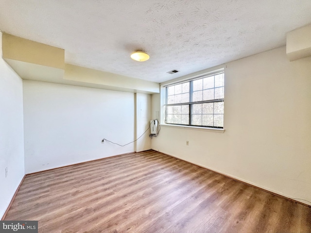 spare room featuring hardwood / wood-style flooring and a textured ceiling