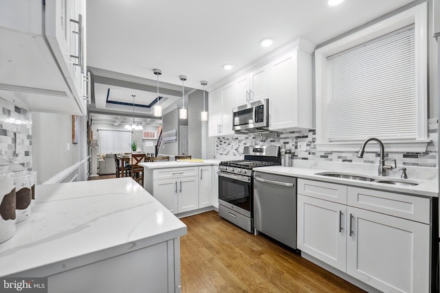 kitchen featuring pendant lighting, white cabinets, sink, appliances with stainless steel finishes, and kitchen peninsula