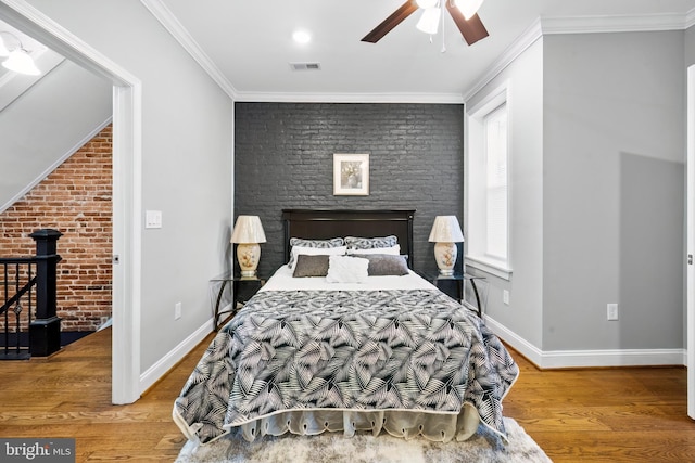 bedroom featuring hardwood / wood-style flooring, ceiling fan, crown molding, and brick wall