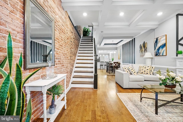 living room featuring coffered ceiling, crown molding, light hardwood / wood-style floors, beam ceiling, and a chandelier