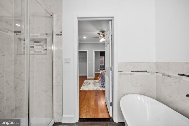 bathroom featuring ceiling fan, separate shower and tub, wood-type flooring, and tile walls