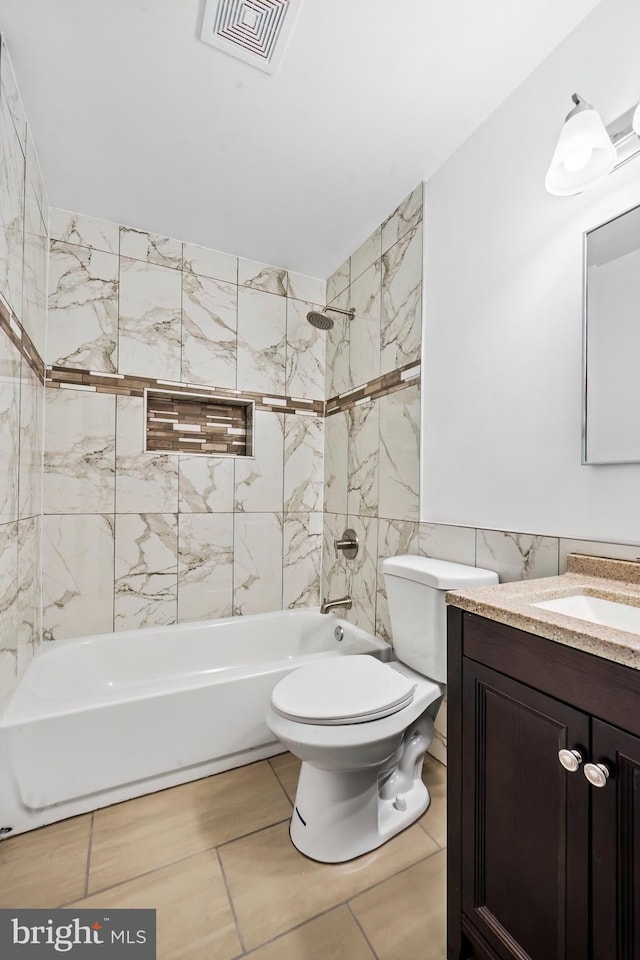 full bathroom featuring vanity, tiled shower / bath combo, tile walls, and toilet