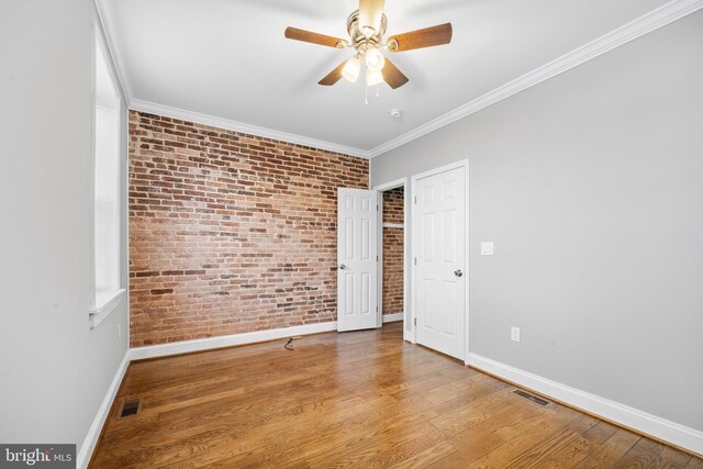 spare room with crown molding, ceiling fan, brick wall, and hardwood / wood-style flooring