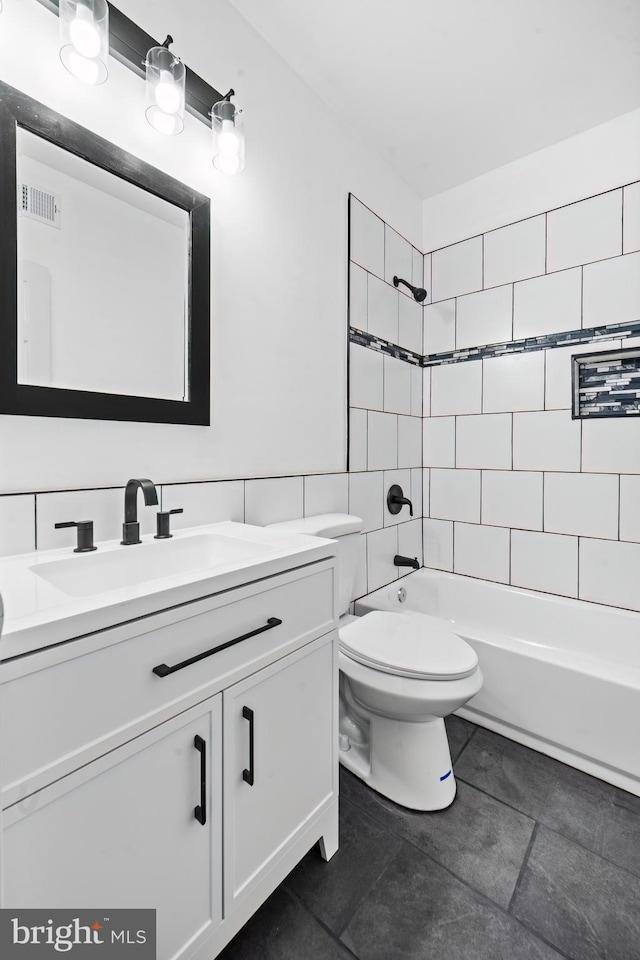 full bathroom featuring vanity, tiled shower / bath, tile patterned flooring, toilet, and tile walls