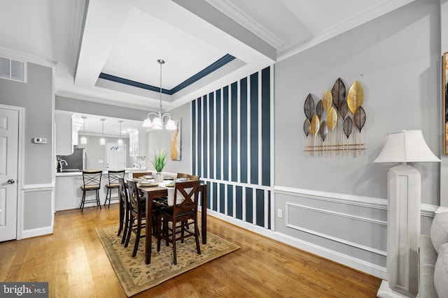 dining area with crown molding, a chandelier, and light hardwood / wood-style floors