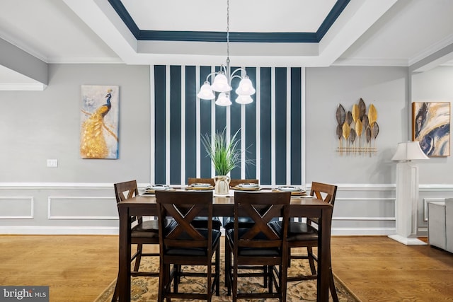 dining area with hardwood / wood-style floors, a notable chandelier, and crown molding