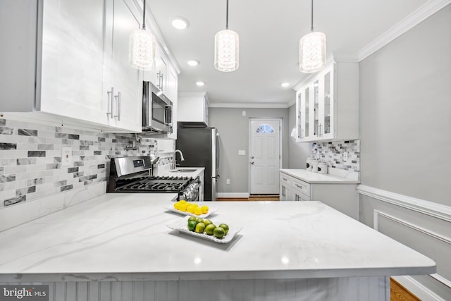 kitchen with backsplash, decorative light fixtures, white cabinetry, and stainless steel appliances