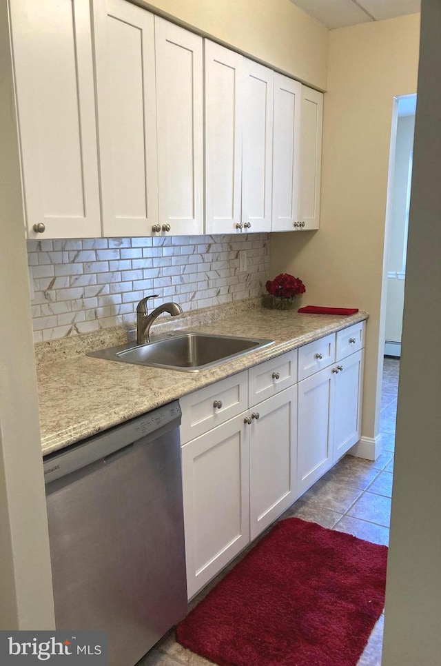 kitchen with sink, tasteful backsplash, white cabinets, stainless steel dishwasher, and light tile patterned flooring