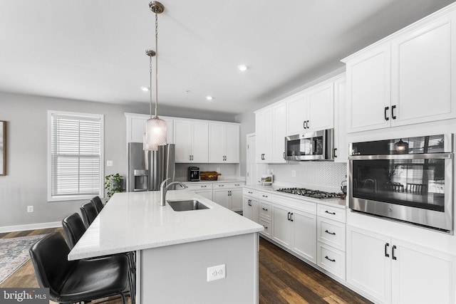 kitchen featuring sink, white cabinets, a center island with sink, pendant lighting, and appliances with stainless steel finishes