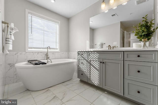 bathroom with vanity, tile walls, and a tub