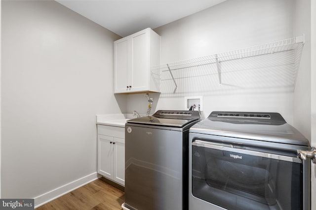 laundry room with sink, cabinets, hardwood / wood-style floors, and washing machine and clothes dryer