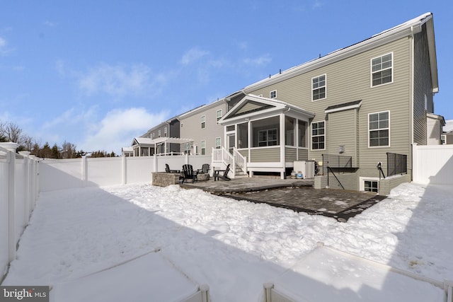 snow covered back of property with a sunroom and central AC unit