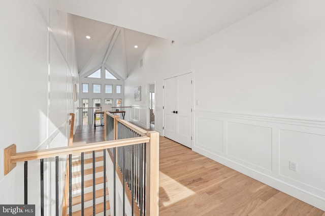 hallway featuring light wood-type flooring and vaulted ceiling