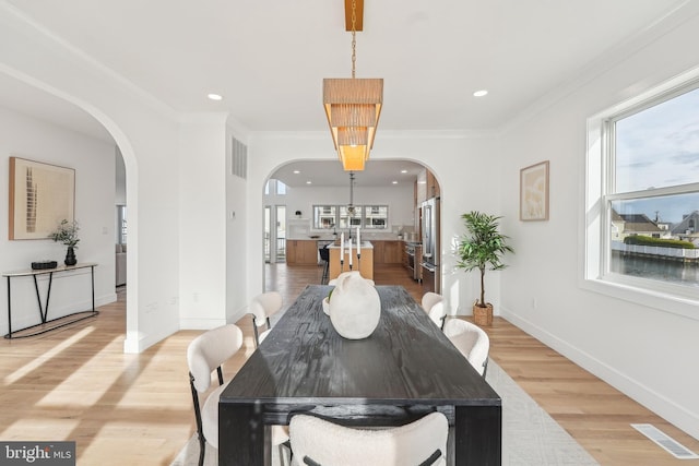 dining space with plenty of natural light, light hardwood / wood-style floors, and crown molding