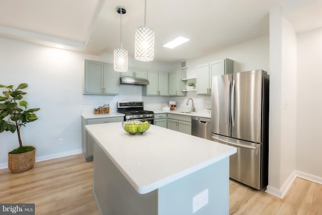 kitchen with decorative backsplash, stainless steel appliances, sink, decorative light fixtures, and a kitchen island