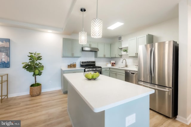 kitchen featuring pendant lighting, a kitchen island, appliances with stainless steel finishes, and light hardwood / wood-style flooring