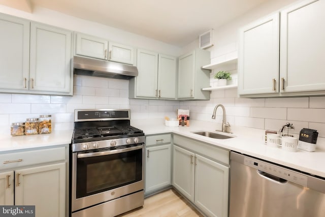 kitchen featuring decorative backsplash, appliances with stainless steel finishes, light hardwood / wood-style floors, and sink