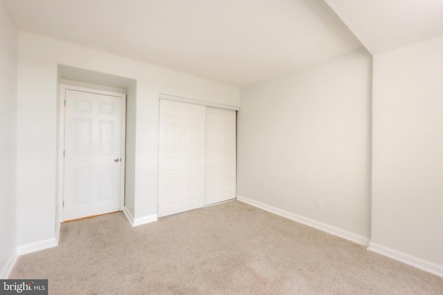 unfurnished bedroom featuring light carpet and a closet