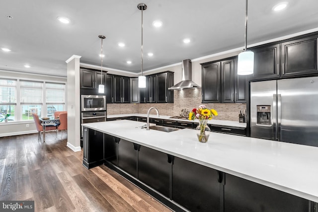 kitchen with sink, wall chimney exhaust hood, stainless steel appliances, crown molding, and decorative light fixtures