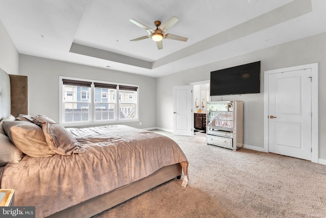 bedroom featuring carpet floors, a tray ceiling, ceiling fan, and ensuite bathroom