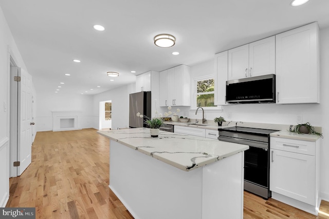 kitchen with light stone countertops, stainless steel appliances, white cabinetry, and a kitchen island