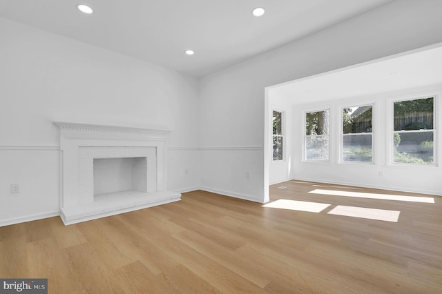 unfurnished living room featuring a fireplace and light hardwood / wood-style flooring