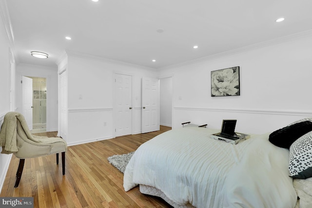 bedroom with wood-type flooring, ensuite bath, and ornamental molding