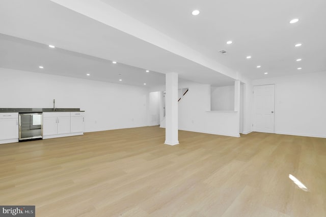 basement featuring light hardwood / wood-style floors, sink, and wine cooler