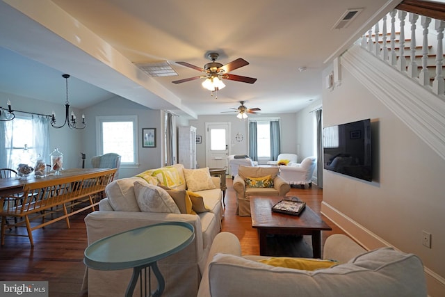 living room with ceiling fan with notable chandelier and dark hardwood / wood-style flooring