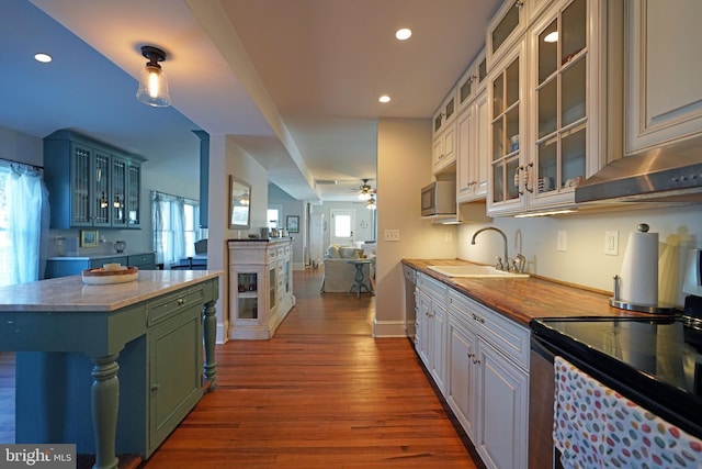 kitchen with appliances with stainless steel finishes, wood-type flooring, sink, white cabinets, and ceiling fan