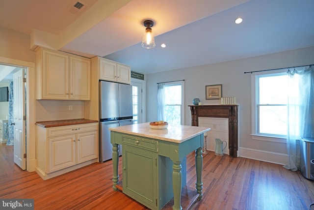 kitchen featuring a kitchen island, light wood-type flooring, green cabinets, and stainless steel refrigerator