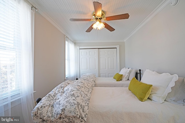 bedroom featuring multiple windows, ornamental molding, a closet, and ceiling fan