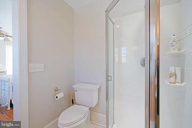 bathroom with ceiling fan, a shower with door, and toilet