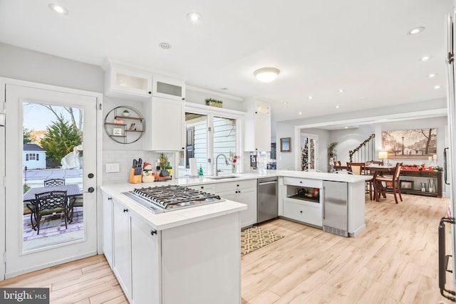 kitchen featuring kitchen peninsula, white cabinetry, sink, and appliances with stainless steel finishes