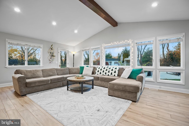 living room with vaulted ceiling with beams, plenty of natural light, and light wood-type flooring