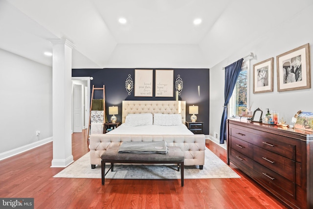 bedroom featuring hardwood / wood-style floors, a tray ceiling, and ornate columns