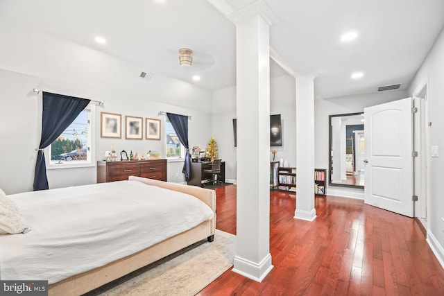 bedroom featuring decorative columns and hardwood / wood-style floors