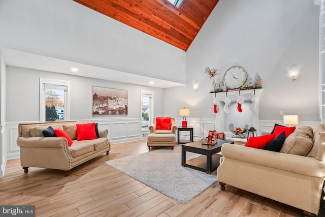 living room with a skylight, wooden ceiling, high vaulted ceiling, and light hardwood / wood-style flooring