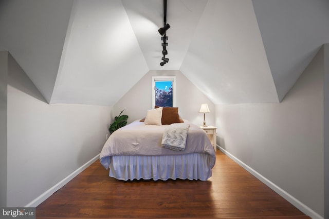 bedroom featuring lofted ceiling, dark hardwood / wood-style flooring, and track lighting