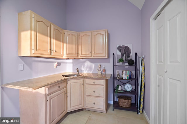 kitchen with light brown cabinets, light tile patterned flooring, and sink