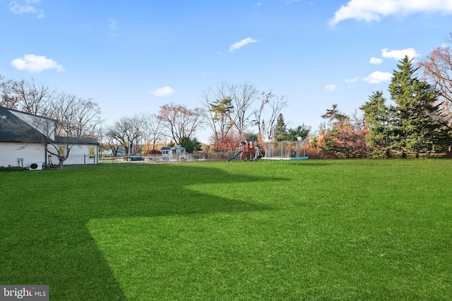 view of yard with a trampoline and a playground